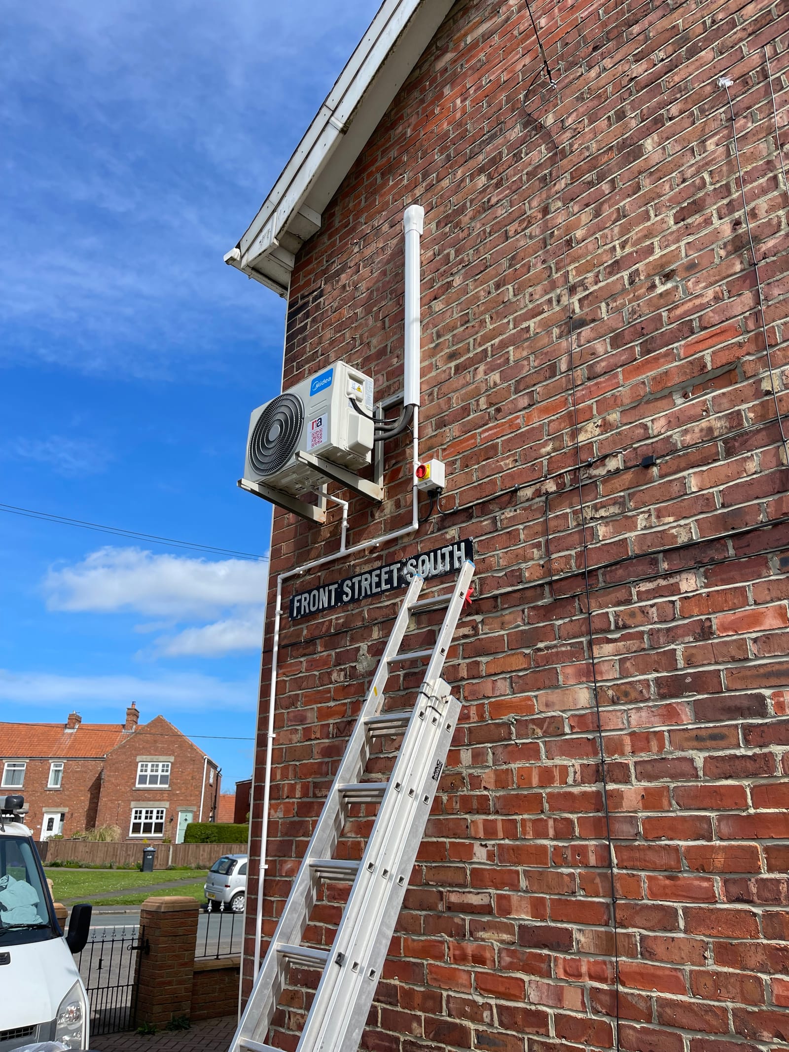 An outdoor air conditioning condenser installed on a brick wall on Front Street