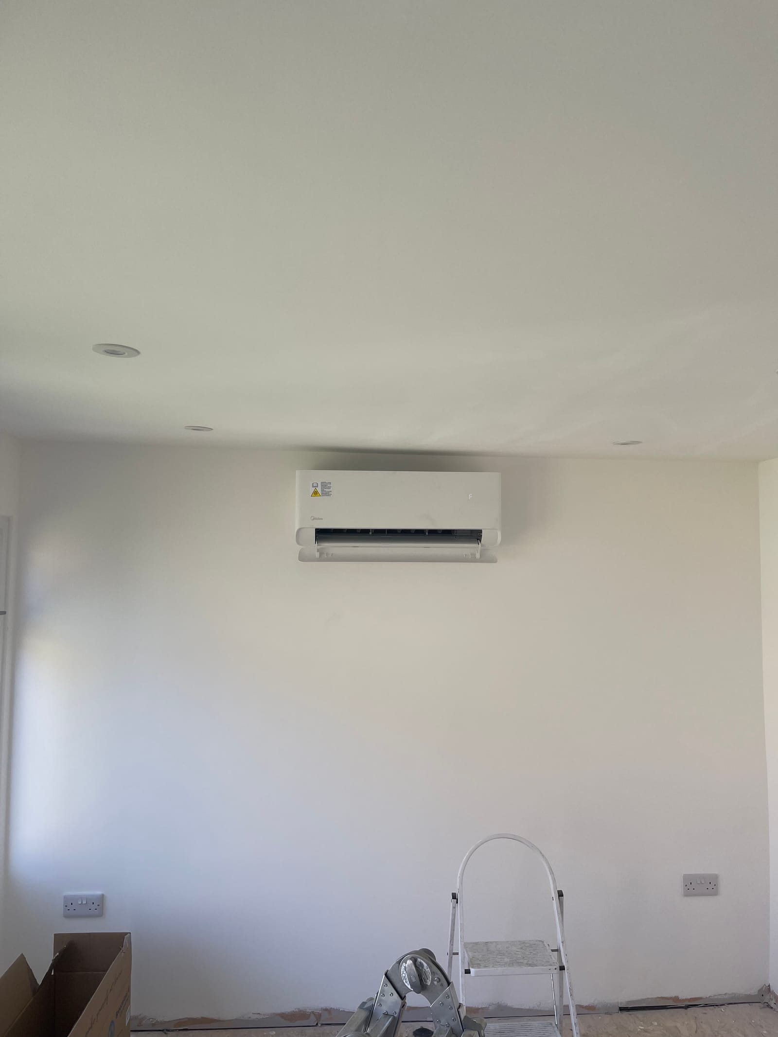 An engineer mid-installation of an interior wall split air conditioning unit