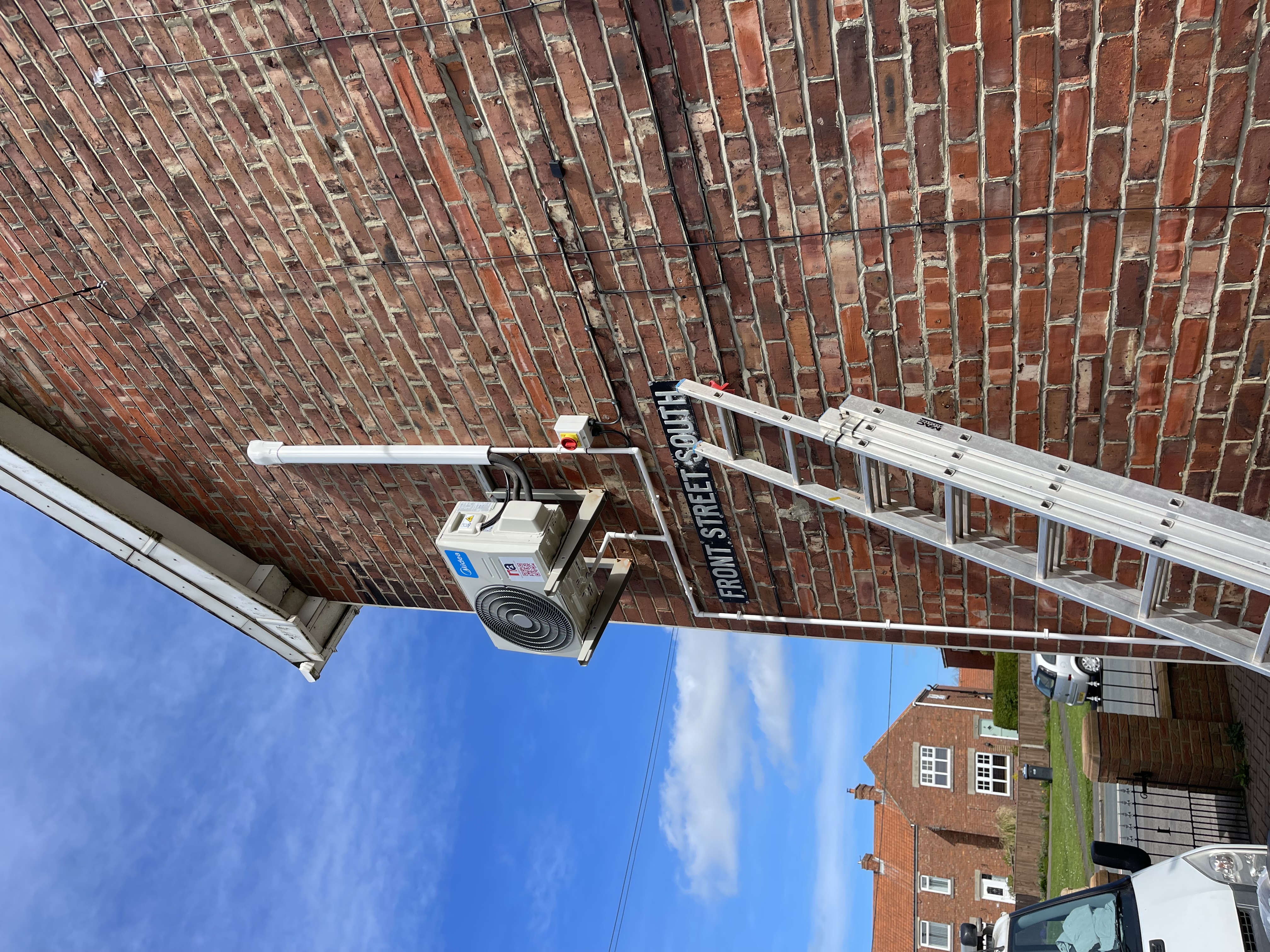 An outdoor air conditioning condenser installed on a brick wall on Front Street