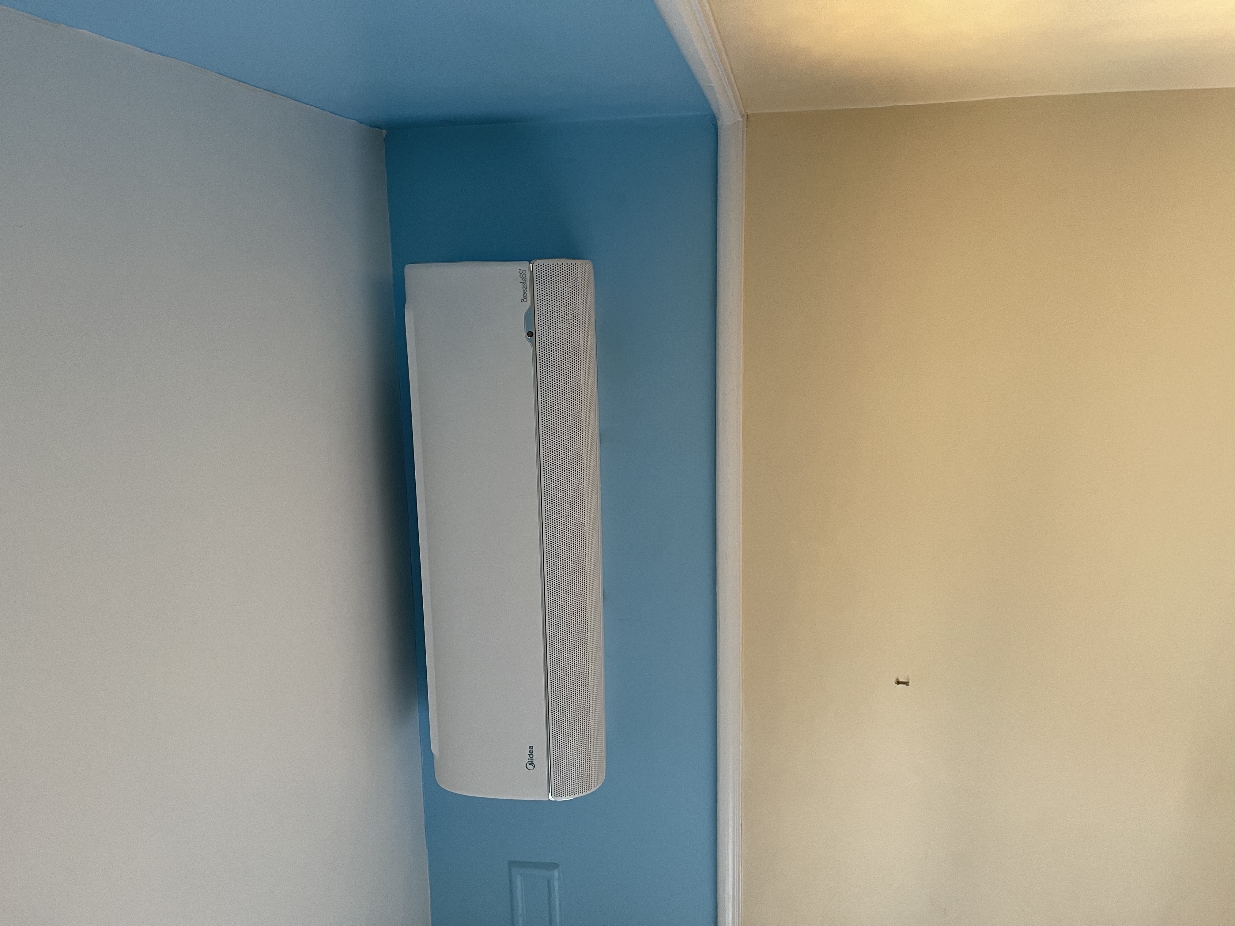 A wall-mounted indoor air conditioning unit installed in a customer's bedroom