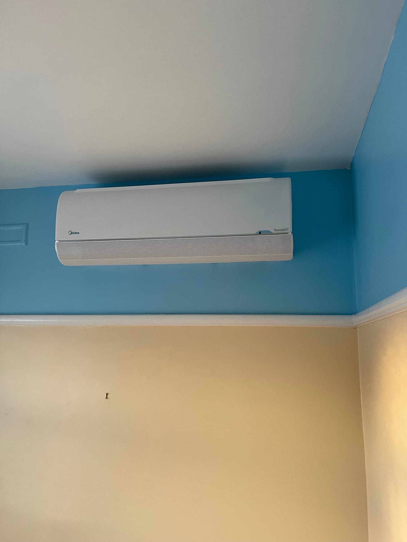 A wall-mounted indoor air conditioning unit installed in a customer's bedroom